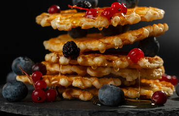 Dripping drops of fresh honey from fresh crispy Belgian waffles with fresh blueberries blackberries and red currants