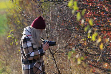Kobieta fotograf, blond włosy wykonująca zdjęcia przyrody jesienią. - obrazy, fototapety, plakaty