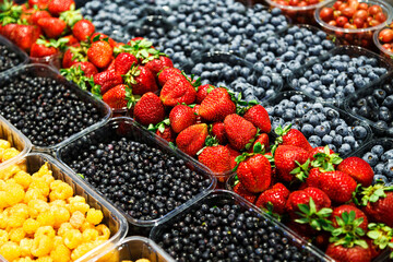 Colourful mix of different fresh berries at market. Raspberries, strawberries, blueberries and bilberries