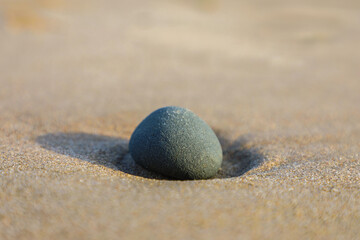 Fototapeta na wymiar Profile view of lone gray rock in the yellow sand