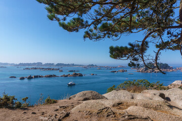 Fototapeta na wymiar Bay of Ploumanac'h on sunny summer day with many small islands of pink granite rocks at high tide, Cote de Granit Rose Brittany , France