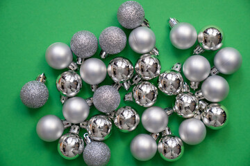 a lot of silver christmas balls, grey baubles on a green background, festive holidays, merry christmas and happy new year