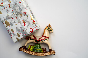 toy horse figure with wrapped gift box, merry christmas and happy new year decorations on a white background, festive holiday surprise, copy space, gifts delivery service