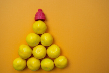 tangerine pyramid with red hat on top, imitation of Christmas tree, fresh yellow and orange citrus...