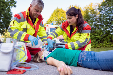 Emergency doctor ventilating injured woman after motorbike accident giving first aid