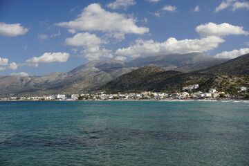 Fototapeta na wymiar Aegean Sea in Crete. White clouds hang over the mountains. Azure water.