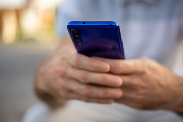 Closeup shot of an unrecognizable man holding mobile phone in hand, blurred background