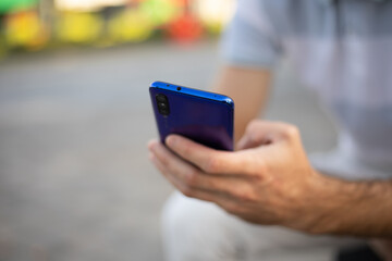 Closeup shot of an man holding mobile phone in hand, blurred background