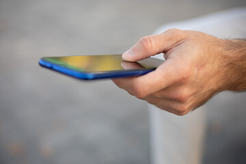 Closeup shot of an unrecognizable man holding mobile phone in hand, blurred background