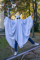 Holiday Halloween. A child dressed as a ghost made of a white sheet and sunglasses stands on a...