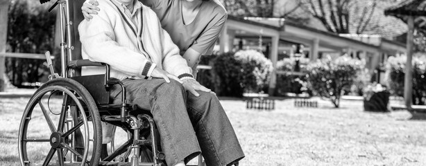 Caucasian senior on the wheelchair smiling with nurse outdoor. Retired elderly people living their life at its best.