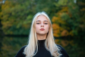 Girl posing in the autumn park with river and trees
