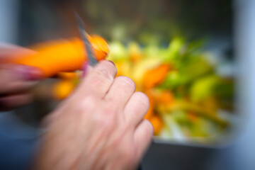 Caucasian housewife woman slices carrots to prepare salad ingredients for dinner meal outdoor