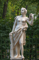 Obraz premium Statue of a woman with a garland of roses in Summer garden, Saint Petersburg, Russia