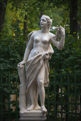 Fototapeta premium Statue of a woman with a garland of roses in Summer garden, Saint Petersburg, Russia