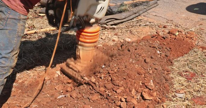 Vibratory plate of tamping machine compactor tool jumps as result compacting to ground while under construction