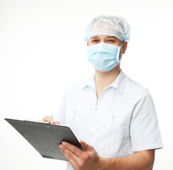 Young male doctor wearing mask writing on clipboard