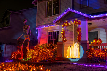 Illuminated Halloween house outdoor decorations with orange and purple garlands, skeleton, pumpkins and ghosts near the house porch