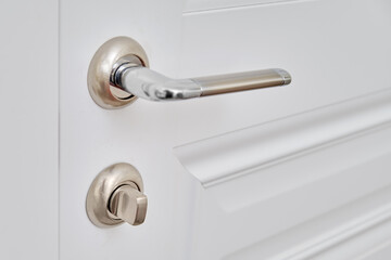 A white door with a lock in the home room and a light switch. Metal door handle in the apartment