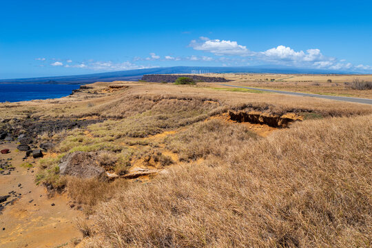 grassland expanse and road along rocky coast winding toward wind farm on horizon at south point hawaii 