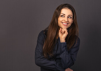 Naklejka na ściany i meble Beautiful confident thinking smiling business woman with folded arms looking up in blue shirt on grey background with empty copy space for text. Closeup