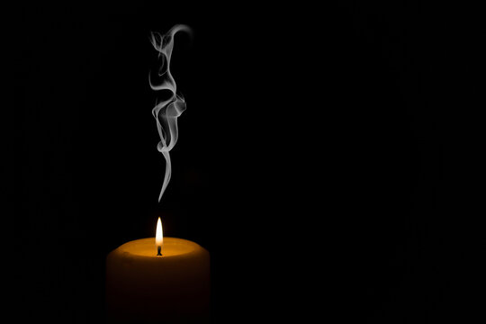 burning candle on black background with smoke