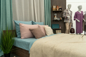 Modern cozy bedroom with a double bed, pillows and a blanket. A store selling beds and sleeping accessories. Mannequin in modern clothes, exhibition hall. Interior of the furniture salon.