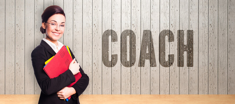 smiling businesswoman in front of a wall with the message COACH