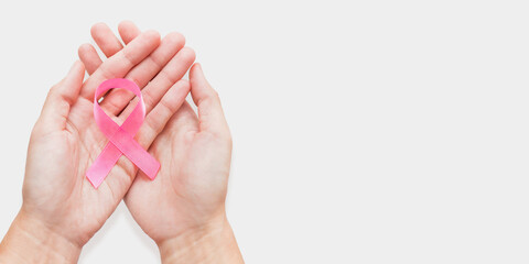 Woman holds bow made of pink ribbon - symbol of breast cancer awareness. World Cancer Day concept on white background with copy space.