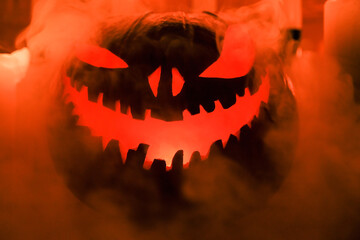 Fototapeta premium Halloween's holiday attributes. Halloween. carved pumpkin. candles . smoke . dark scene. pumpkin head silhouettes.