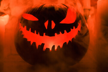 Fototapeta premium Halloween's holiday attributes. Halloween. carved pumpkin. candles . smoke . dark scene. pumpkin head silhouettes.