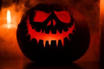 Fototapeta premium Halloween's holiday attributes. Halloween. carved pumpkin. candles . smoke . dark scene. pumpkin head silhouettes.