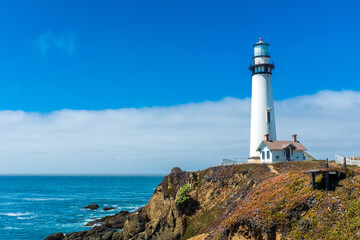 Fototapeta na wymiar Bright lighthouse on the northern California coast with smooth cloud formation