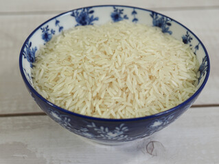 long basmati rice in a blue bowl on white wooden background