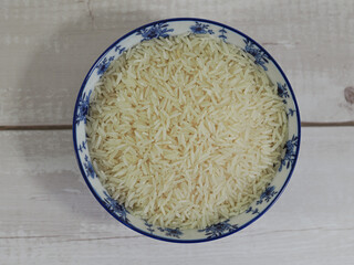 long basmati rice in a blue bowl on white wooden background. Top view