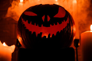 Fototapeta premium Halloween's holiday attributes. Halloween. carved pumpkin. candles . smoke . dark scene. pumpkin head silhouettes.