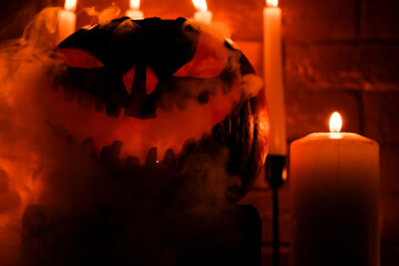 Fototapeta premium Halloween's holiday attributes. Halloween. carved pumpkin. candles . smoke . dark scene. pumpkin head silhouettes.