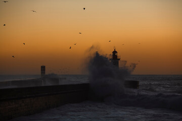 View of Lighthouse with huge wave at Atlantic during amazing sunset, Porto, Portugal.