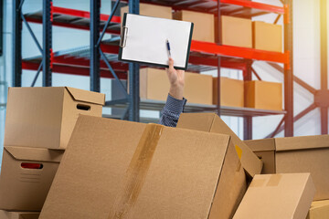 Warehouse revision. Hand with sheet paper among boxes. Mess cardboard boxes. Concept is revision...