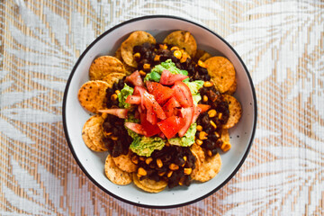 healthy plant-based food, vegan mexican bean nachos with corn chips guacamole and tomato salsa