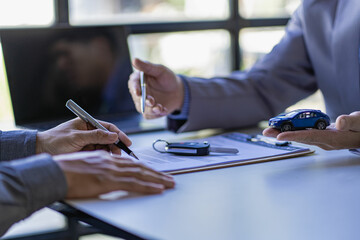 Obraz premium Car rental agent managers with new car owners sign a good rental agreement after passing vehicle financing.