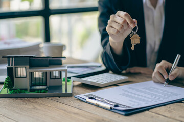 Sales representatives hand out the house keys to customers after signing a contract to buy a house or rent a new home on the table. concept of buying a house