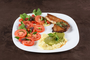 Fototapeta na wymiar fried tilapia fish filet served on plate with tomato salad and mashed potatoes with herb pesto
