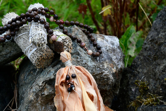 An image of a handmade mala necklace with wooden beads draped across grey rocks.