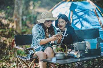 Asian pretty woman and friend use smartphone selfie on camping