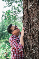 Portrait of Happy Asian man hugging a tree in forest