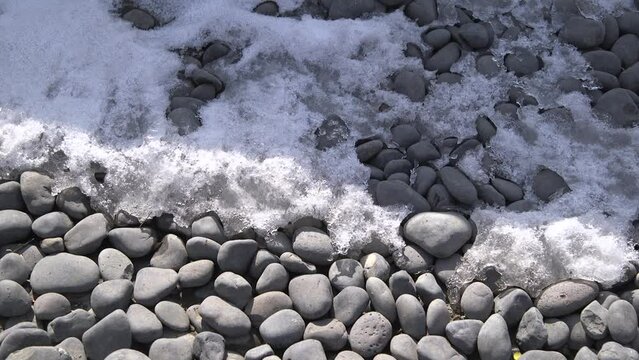 Snow melting during a sunny morning over a pebble road in China.