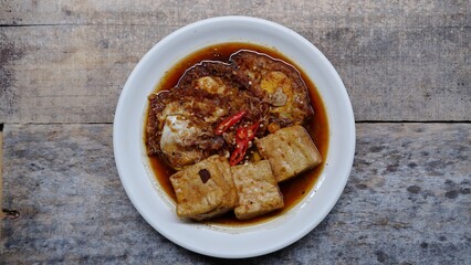 Semur telur dan tahu. Is Indonesian traditional side dish made with sunny side up and tofu cooked with soy sauce and some spices like cinnamon, coriander, pepper, garlic, shallots and chili 
