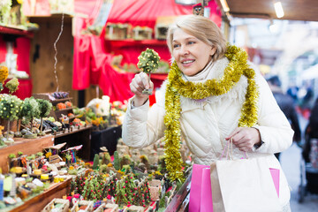 Woman is preparing for Christmas and choosing decorations for her house outdoor.