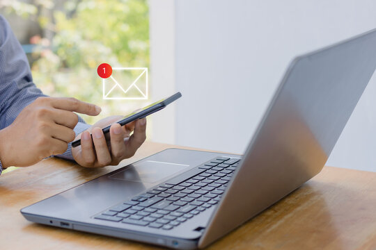 Online communication business technology concept. Email, send, receive, inbox, Hand of businessman using mobile smartphone in home office with notification 1 new email alert sign icon pop up.